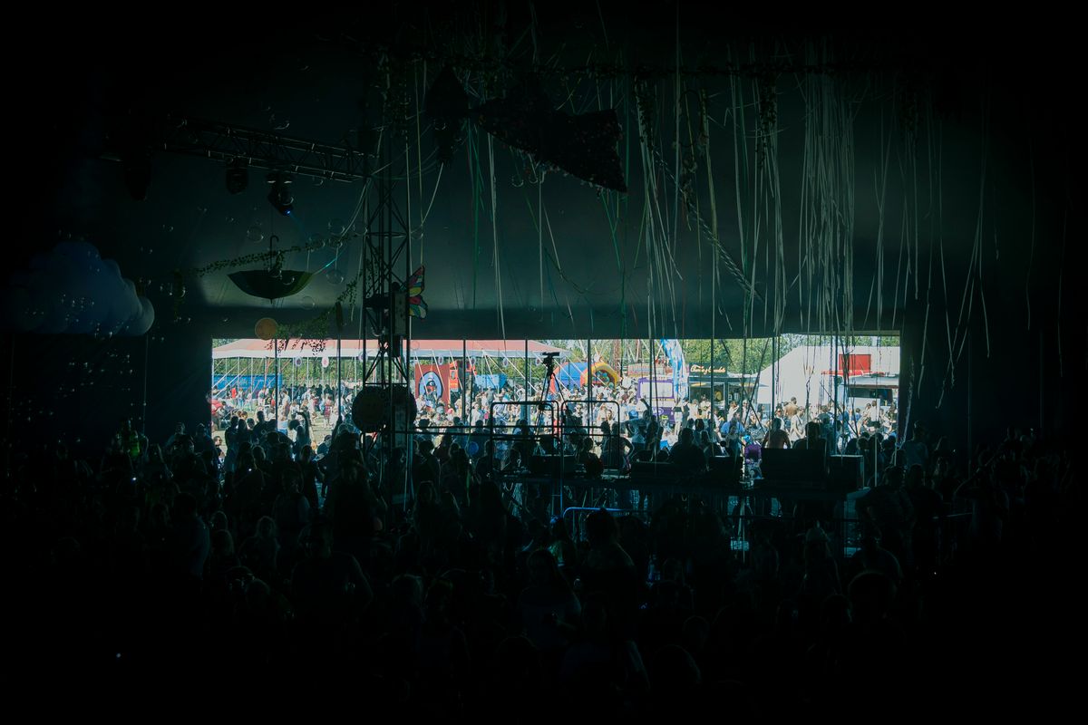 A crowd facing a colorful outdoor live-music stage